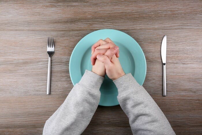 Man holding hands above empty plate