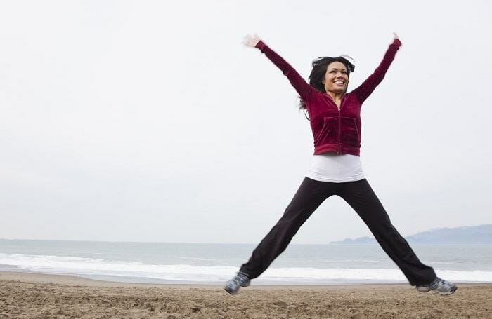 Woman doing jumping jacks on the beach