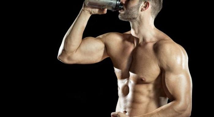 Man drinking weight gainer on black background