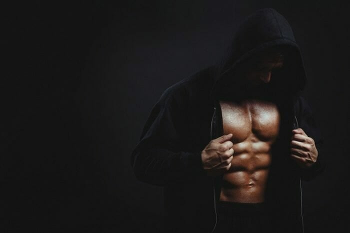 Man wearing black hood on black background