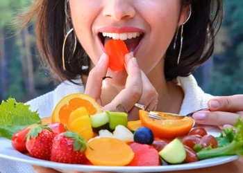A woman eating a plate of fruits