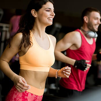 A couple at the gym doing cardio together