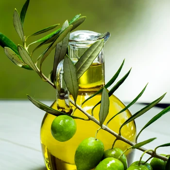 Olives with leaves and a bottle filled with olive extract