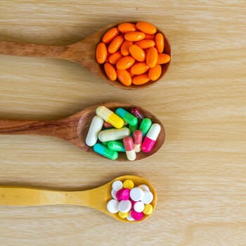 Supplement pills on wooden spoons