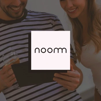 A couple holding a tablet with an overlayed noom logo