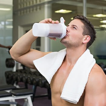 A muscular man drinking protein shake at the gym