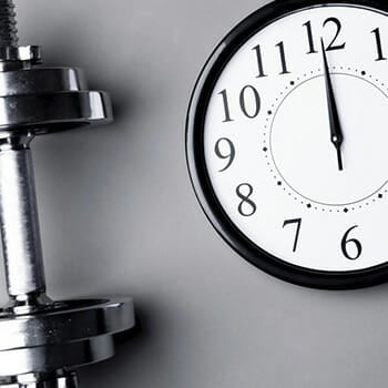 Close up shot of a clock with a dumbbell on the side