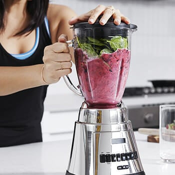 A person blending fruits and protein shake at a home kitchen