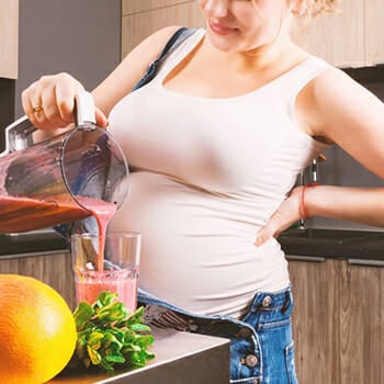 A pregnant woman making a shake at home