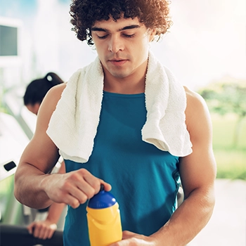 Athlete with face towel on his back holding supplement drink
