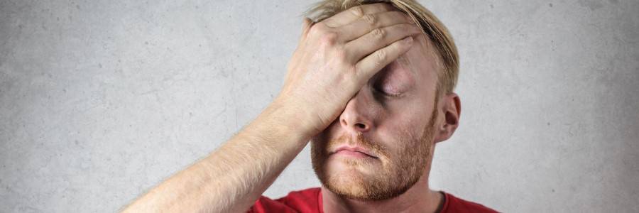 A man with a headache covering his face