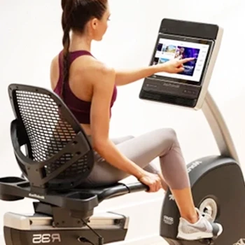 A woman using a recumbent bike with feedback screen