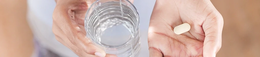 A top view of a woman holding a collagen supplement and a glass of water