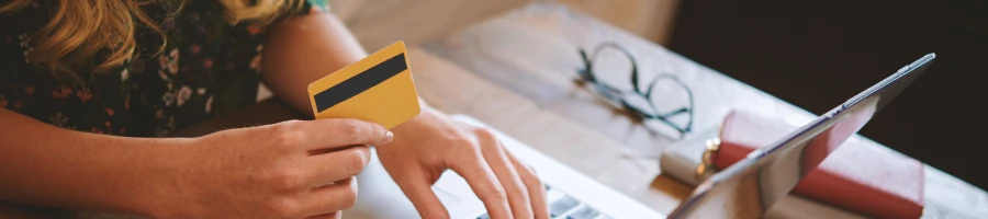 A person holding a credit card near a laptop