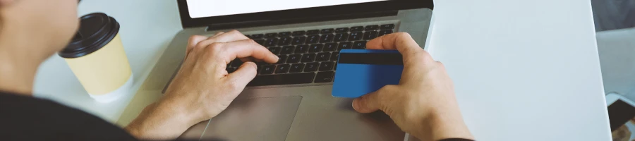 A person holding a credit card and working on a laptop