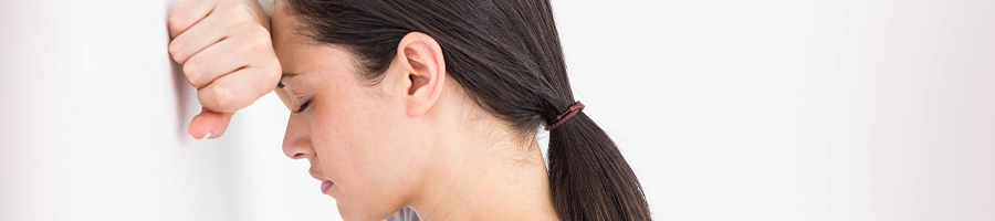 Woman leaning on wall from having a headache