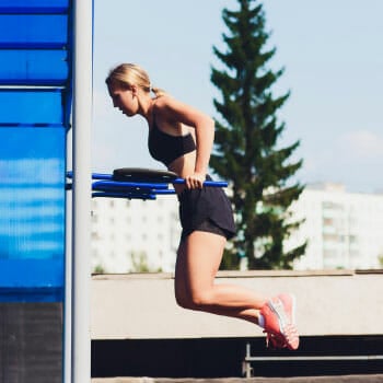 woman doing dips outdoors