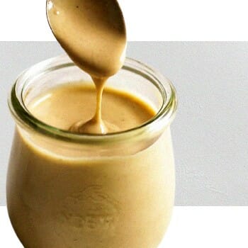 scooping out tahini sauce from a jar