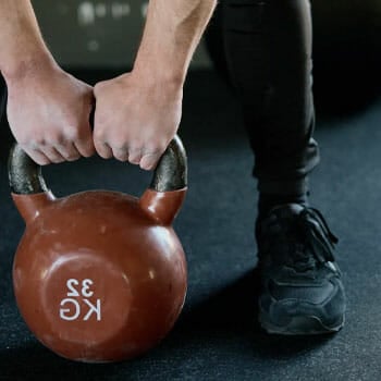 man pulling up a kettlebell with two hands