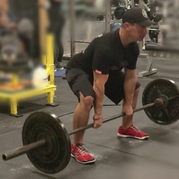 man inside a gym lifting a heavy barbell