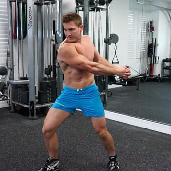 shirtless man using the cable machine inside a gym