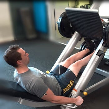 man working out his legs using a leg press machine