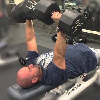 man laying down doing dumbbell press