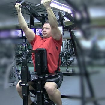 man in a red shirt working out with a machine