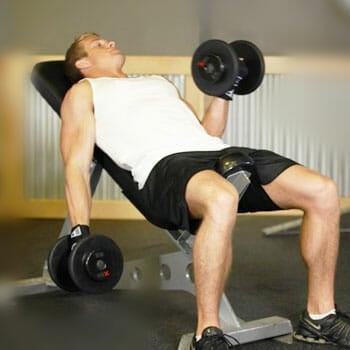 man in an incline position lifting dumbbells