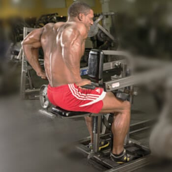 shirtless man using a dip machine in a gym