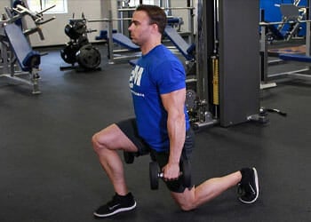 A man doing walking lunges with dumbbells