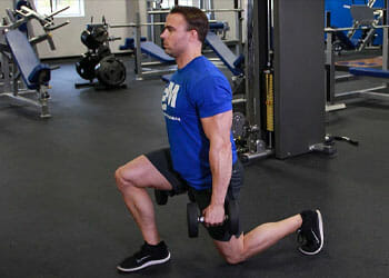 A man doing walking lunges with dumbbells