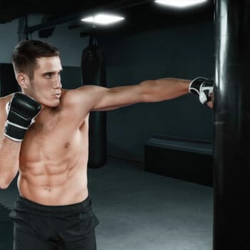 shirtless man boxing with a punching bag