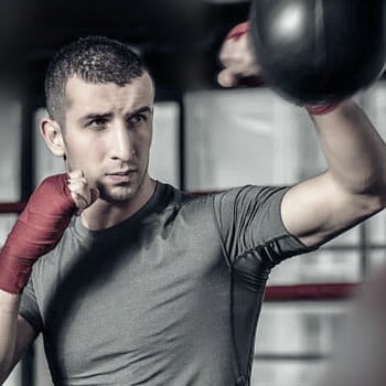 tall man using a speed bag inside a gym