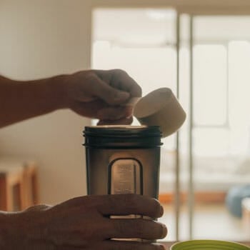 close up image of a man pouring protein powder into a water jug