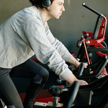 man wearing a grey sweatshirt using a bike inside a gym