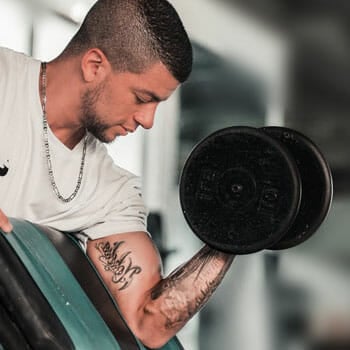 man in a white shirt doing dumbbell workout