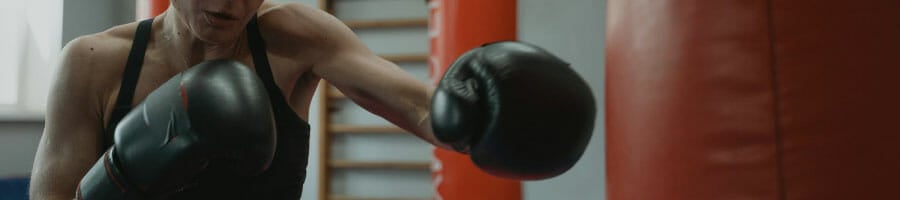 person with boxing gloves working out using a punching bag