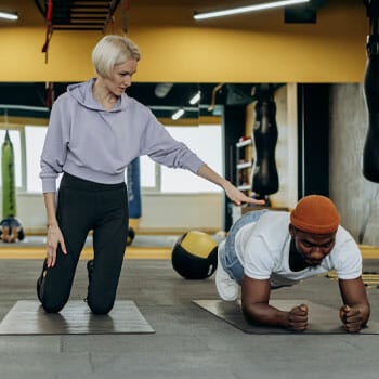 man planking while a woman assists