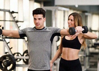 woman teaching a man how to use dumbbells