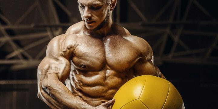 A muscular man holding a volleyball