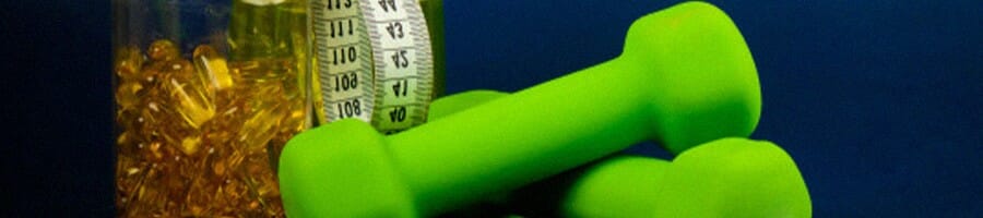 green dumbbells, measuring tape and a jar of pills