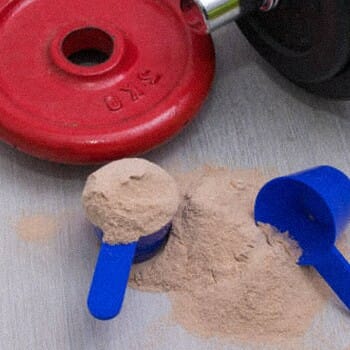 Creatine powder spilled with a dumb bell on side