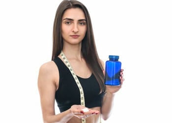 A fit woman holding an empty pill bottle