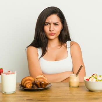 woman thinking and a table with different food on top