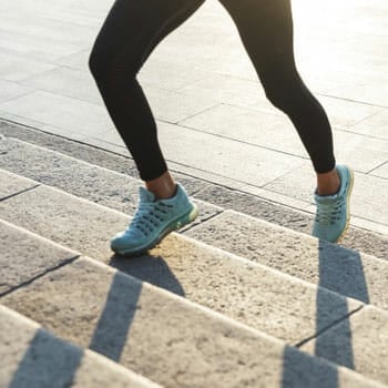 lower leg view of a woman jogging up the stairs