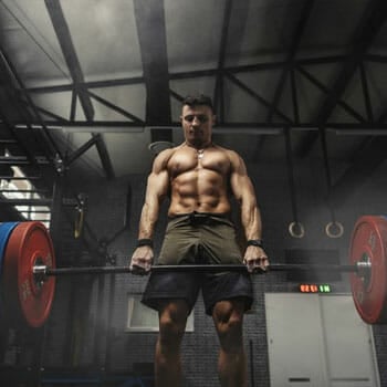 shirtless man lifting a heavy barbell