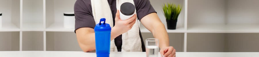 man holding a container with a jug and water glass on the table