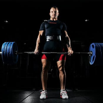 bodybuilder practicing barbell shrugs in a gym