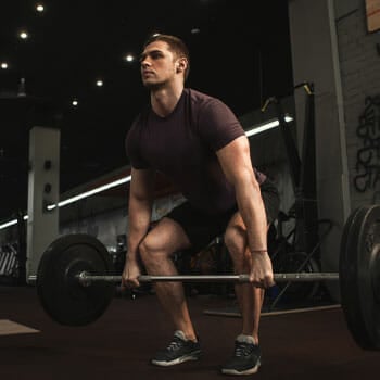 man about to lift a barbell inside a gym